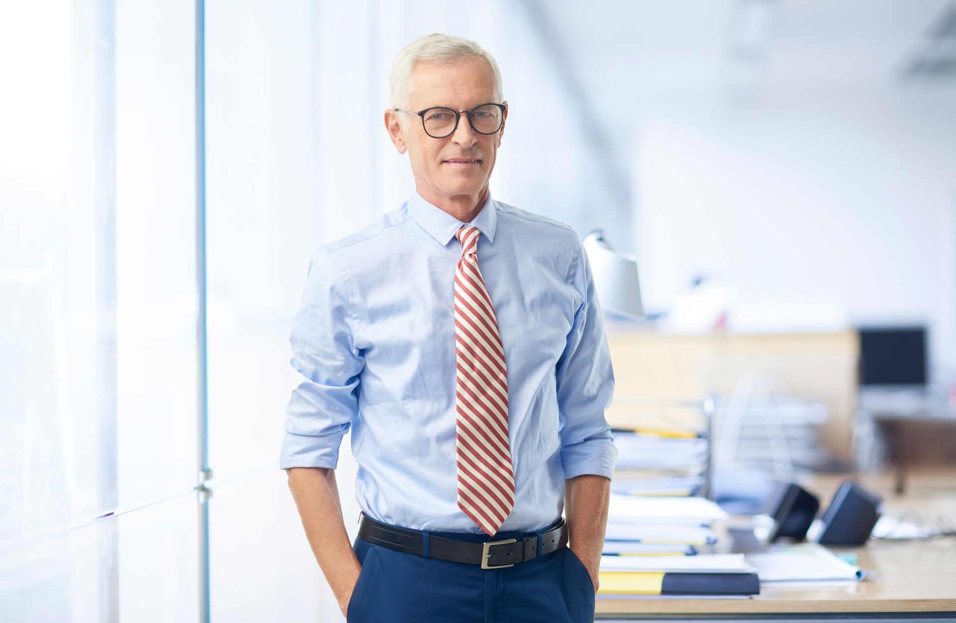Senior businessman wearing rolled up sleeves shirt and tie while standing at the office.