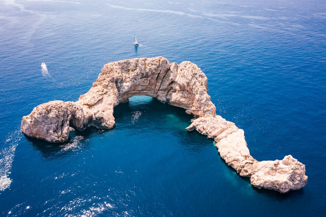 person standing on rock formation in the middle of the sea during daytime